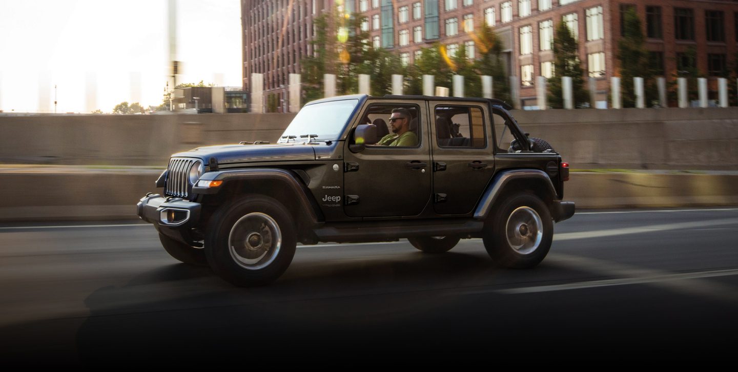 The 2022 Jeep Wrangler Sahara being driven on a city street.